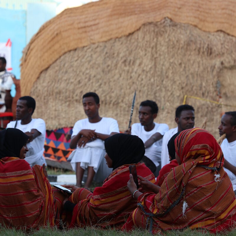 University students sit in front of Somali traditional house